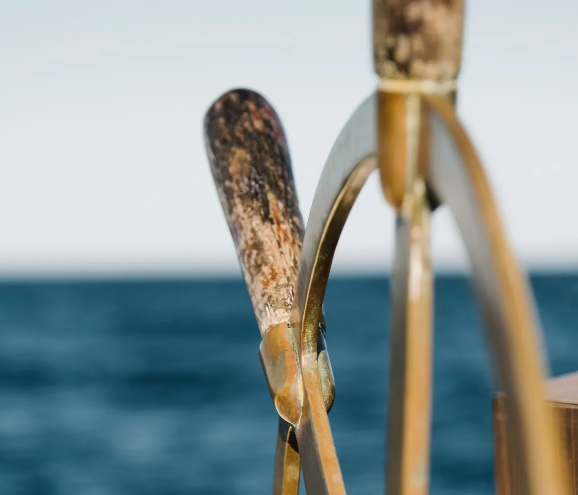 Detalle de los remos cruzados y el escálamo de una embarcación, con el mar al fondo