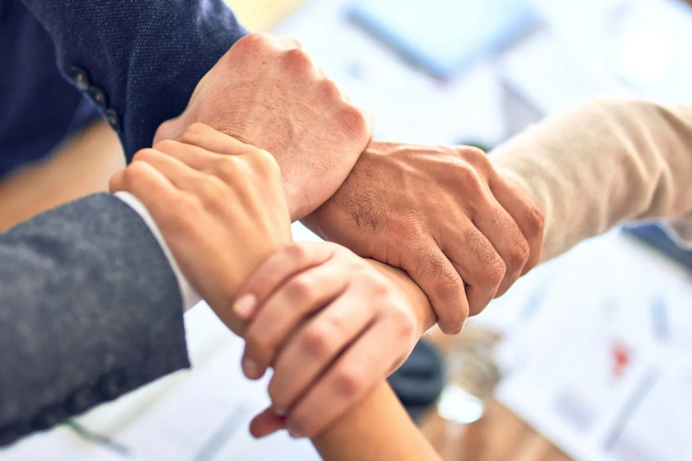 Manos de un equipo entrelazadas en señal de unión